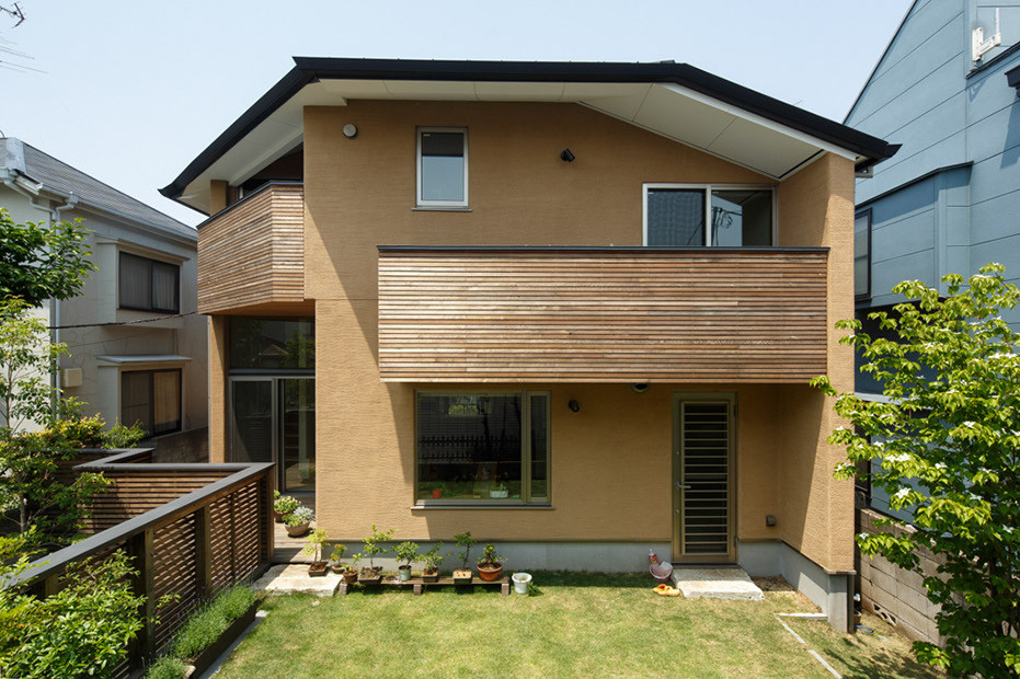 Imagen de fachada de casa marrón moderna de tamaño medio de tres plantas con revestimiento de estuco, tejado a cuatro aguas y tejado de metal