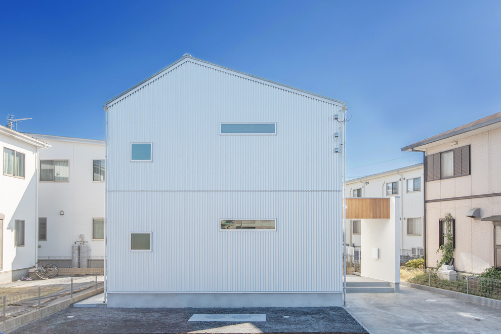 Imagen de fachada de casa gris minimalista pequeña a niveles con revestimiento de metal, tejado a dos aguas y tejado de metal