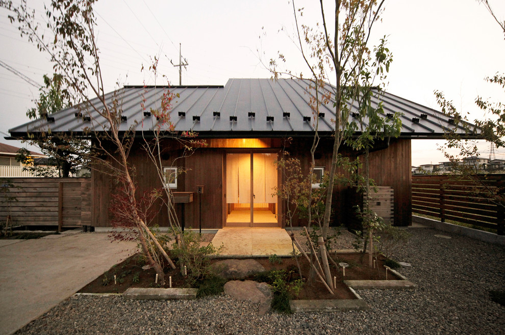 Brown world-inspired bungalow detached house in Other with wood cladding and a metal roof.
