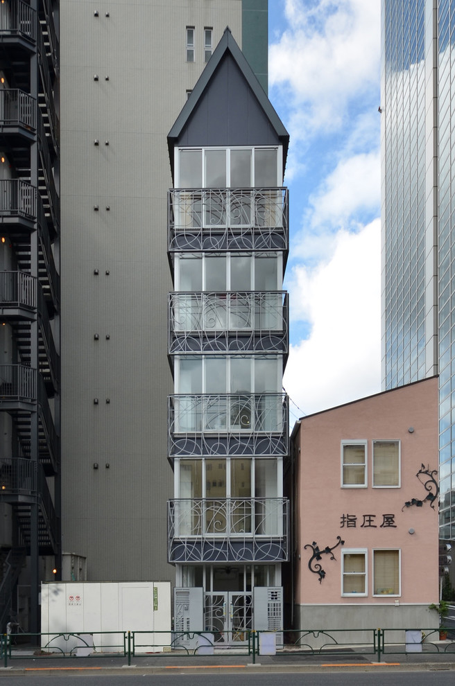 Black world-inspired glass house exterior in Tokyo with three floors and a pitched roof.