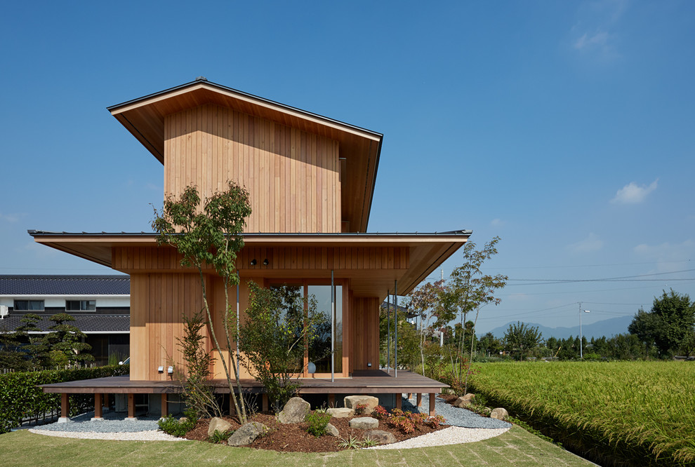 Cette image montre une façade de maison marron asiatique en bois avec un toit à deux pans.