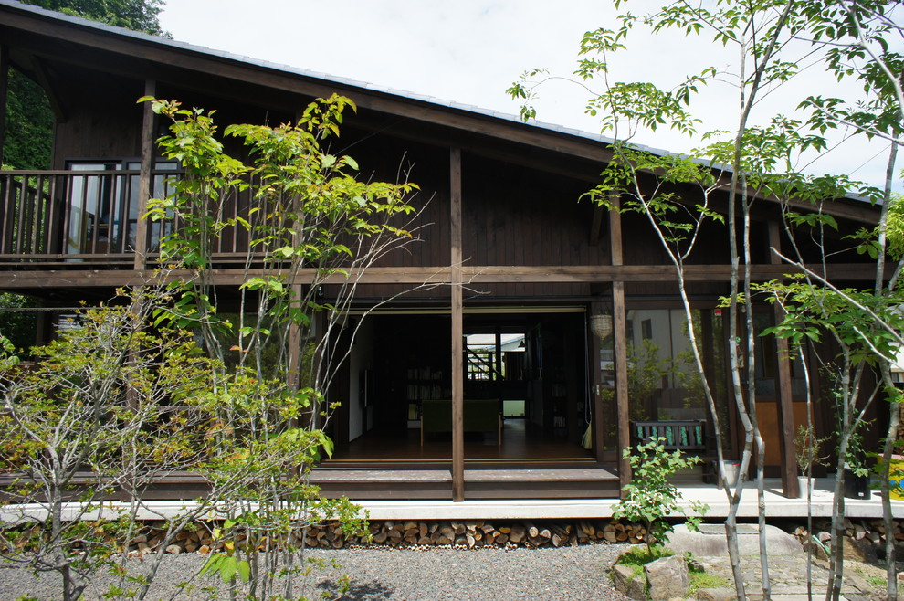 Cette photo montre une façade de maison marron nature en bois à un étage et de taille moyenne avec un toit en appentis et un toit en tuile.