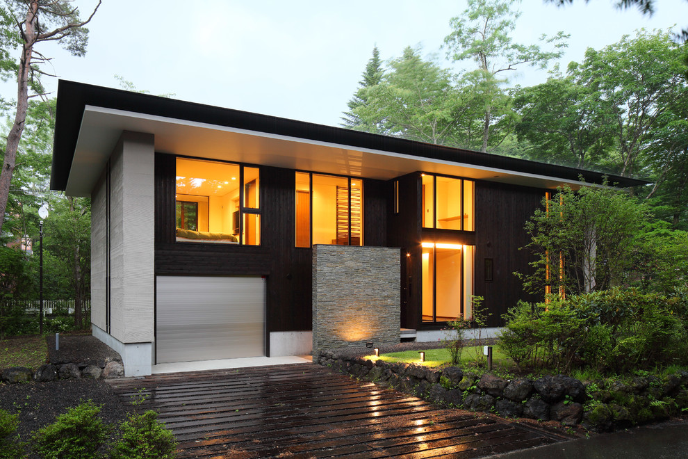 На фото: деревянный, черный частный загородный дом среднего размера в стиле модернизм с разными уровнями, вальмовой крышей и металлической крышей