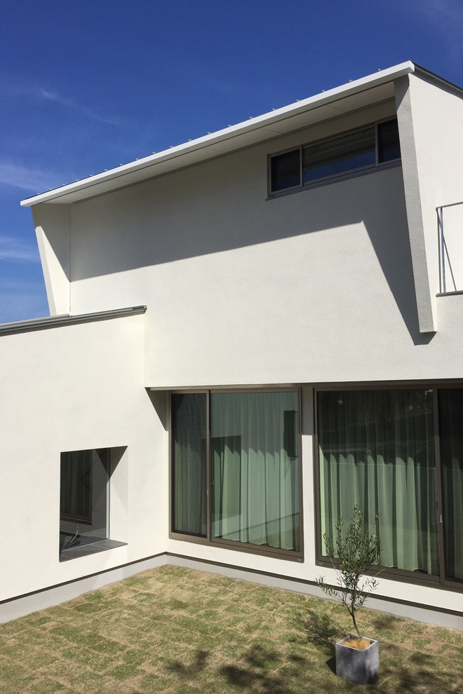 Свежая идея для дизайна: двухэтажный, белый частный загородный дом среднего размера в стиле модернизм с облицовкой из цементной штукатурки, односкатной крышей и металлической крышей - отличное фото интерьера