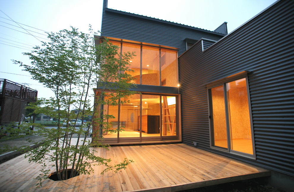 Foto på ett mellanstort funkis grått hus, med två våningar, metallfasad, pulpettak och tak i metall