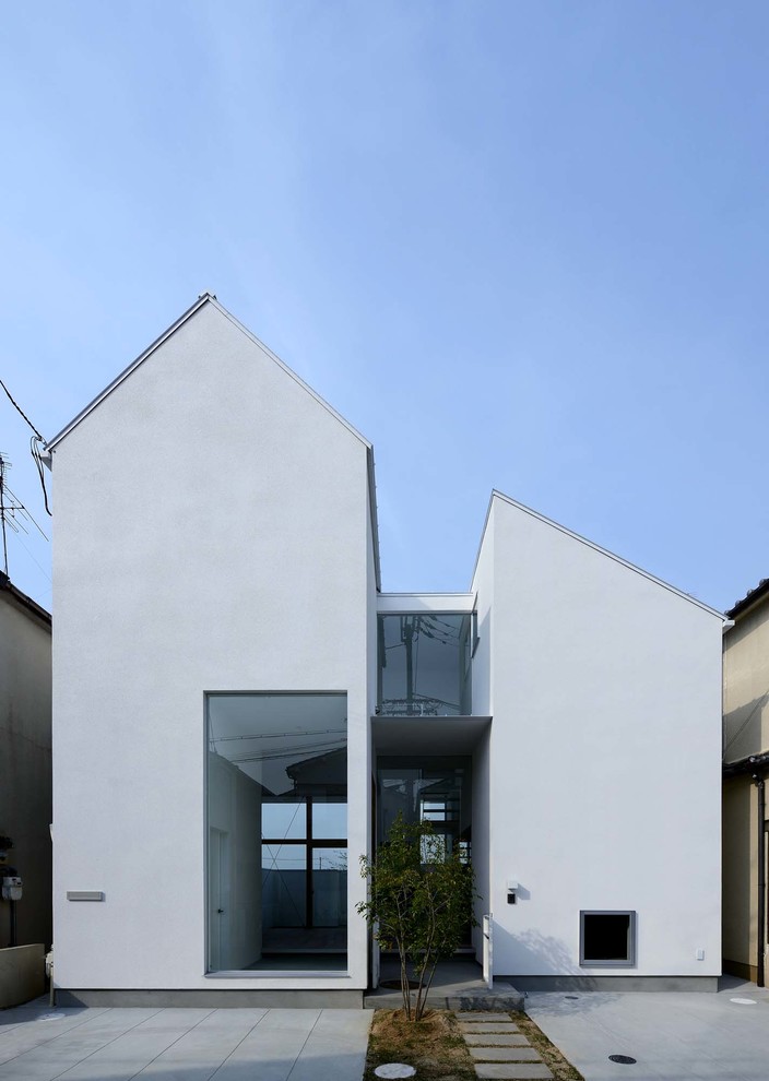 Foto della facciata di una casa bianca contemporanea a piani sfalsati con rivestimento in cemento