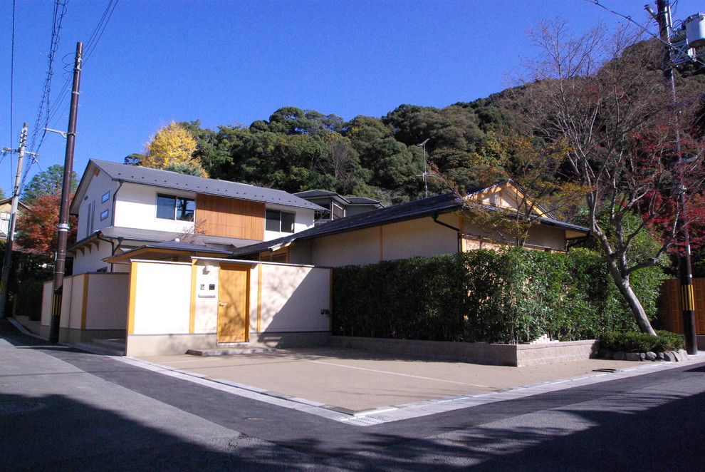 Ejemplo de fachada de casa beige asiática de dos plantas con tejado de metal