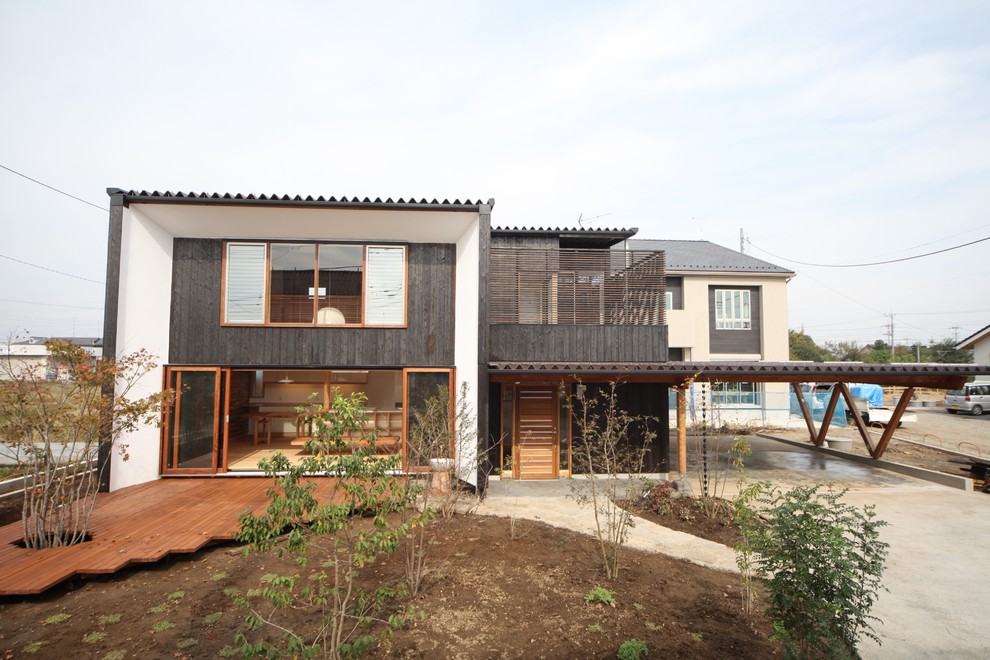 Immagine della facciata di una casa piccola nera etnica a due piani con rivestimento in legno e copertura in metallo o lamiera