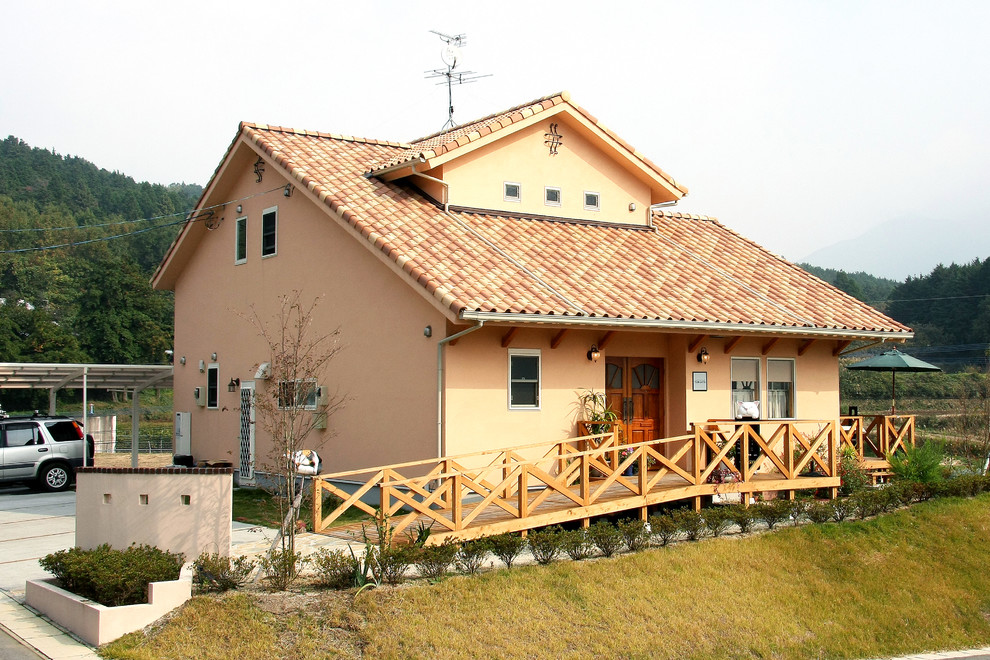 Идея дизайна: оранжевый дом в средиземноморском стиле с двускатной крышей и черепичной крышей