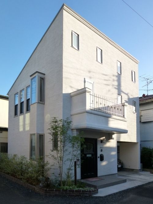 Small and white traditional two floor house exterior in Tokyo Suburbs with a lean-to roof.