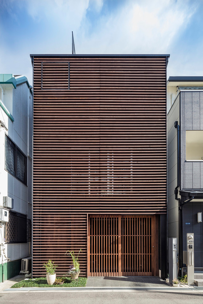 На фото: трехэтажный, деревянный, коричневый дом в современном стиле с плоской крышей с