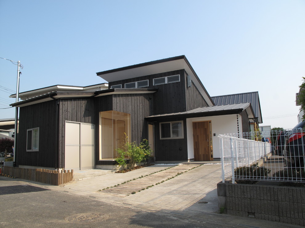 Small and black modern bungalow detached house in Other with wood cladding and a metal roof.