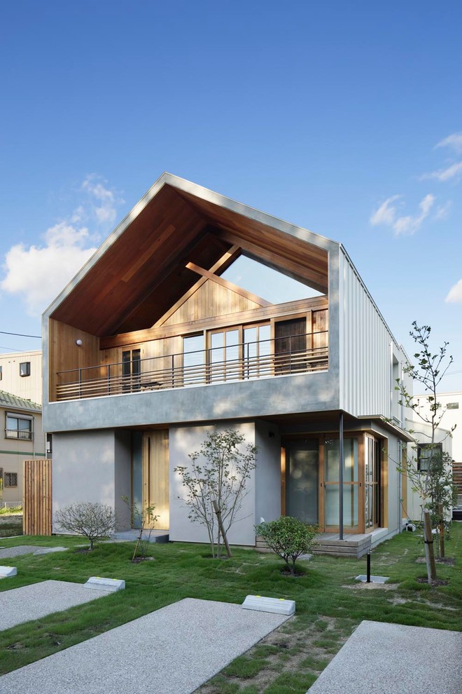 Réalisation d'une façade de maison grise design à un étage avec un revêtement mixte et un toit à deux pans.