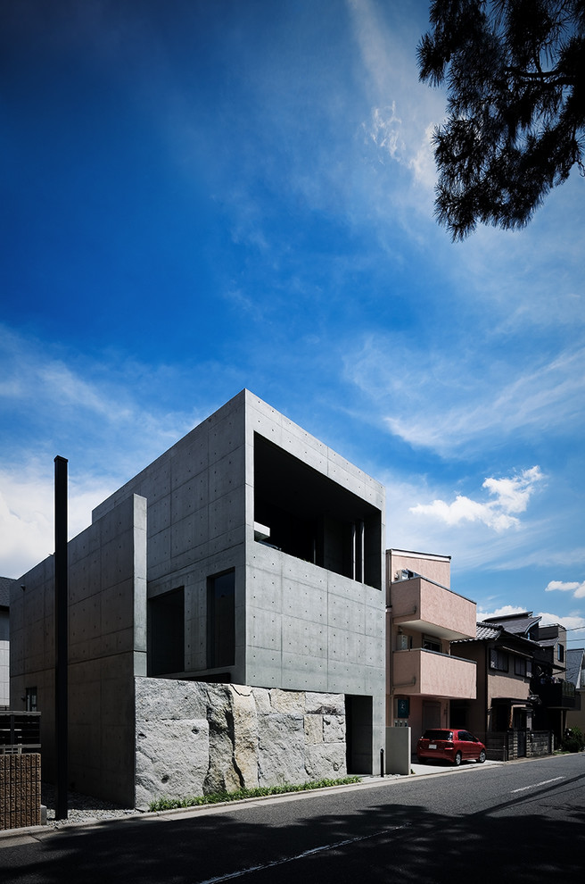 На фото: трехэтажный, серый частный загородный дом в стиле лофт с облицовкой из бетона и плоской крышей с