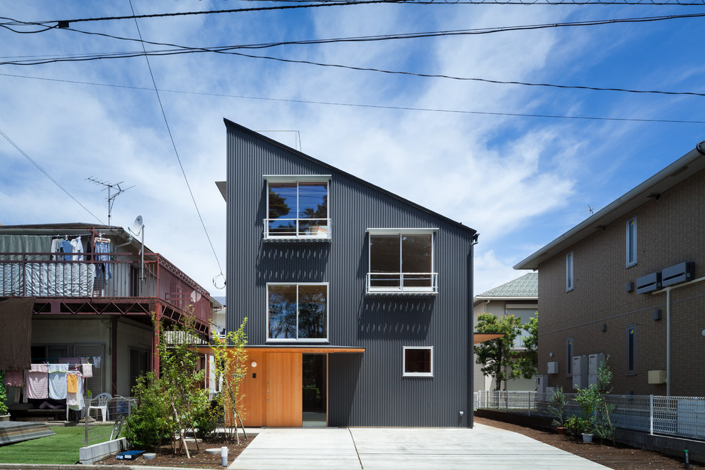 Cette image montre une façade de maison métallique et noire minimaliste de taille moyenne et à un étage avec un toit en appentis et un toit en métal.