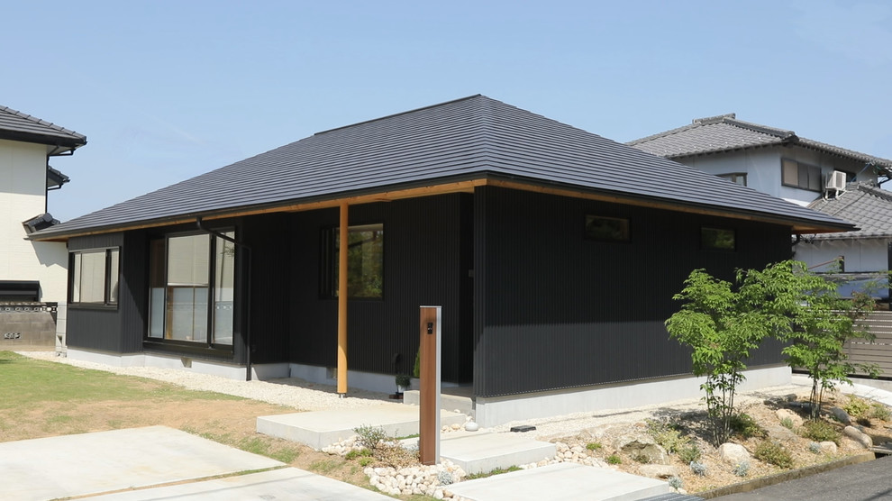 Inredning av ett asiatiskt litet svart hus, med allt i ett plan, metallfasad, valmat tak och tak i metall
