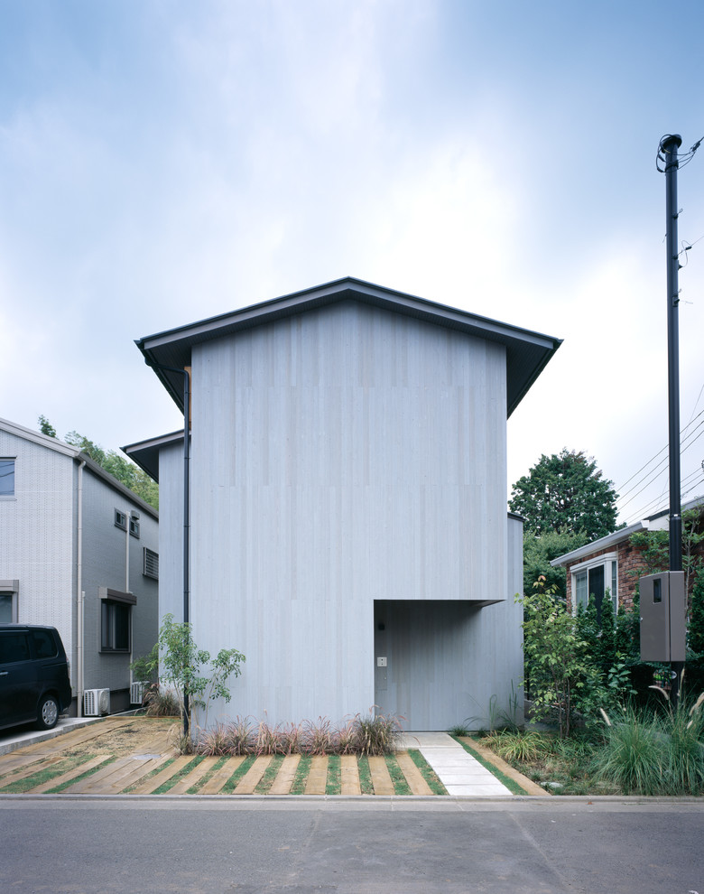 Cette image montre une façade de maison grise minimaliste en bois à un étage avec un toit à deux pans et un toit en métal.