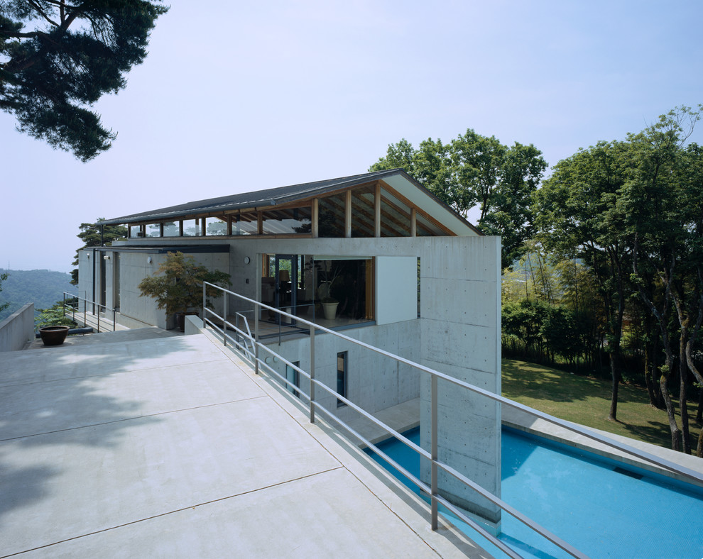 На фото: двухэтажный, серый дом среднего размера в стиле лофт с облицовкой из бетона и двускатной крышей с
