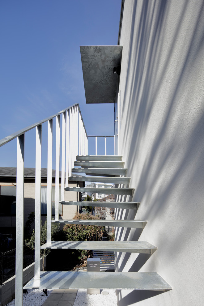 Dreistöckiges Modernes Wohnung mit weißer Fassadenfarbe, Pultdach und Blechdach in Tokio