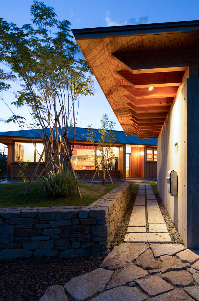 Cette image montre une façade de maison beige asiatique en bois de taille moyenne et de plain-pied avec un toit à quatre pans et un toit en métal.