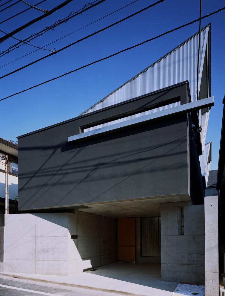 На фото: двухэтажный, черный частный загородный дом среднего размера в стиле модернизм с облицовкой из цементной штукатурки, односкатной крышей и металлической крышей