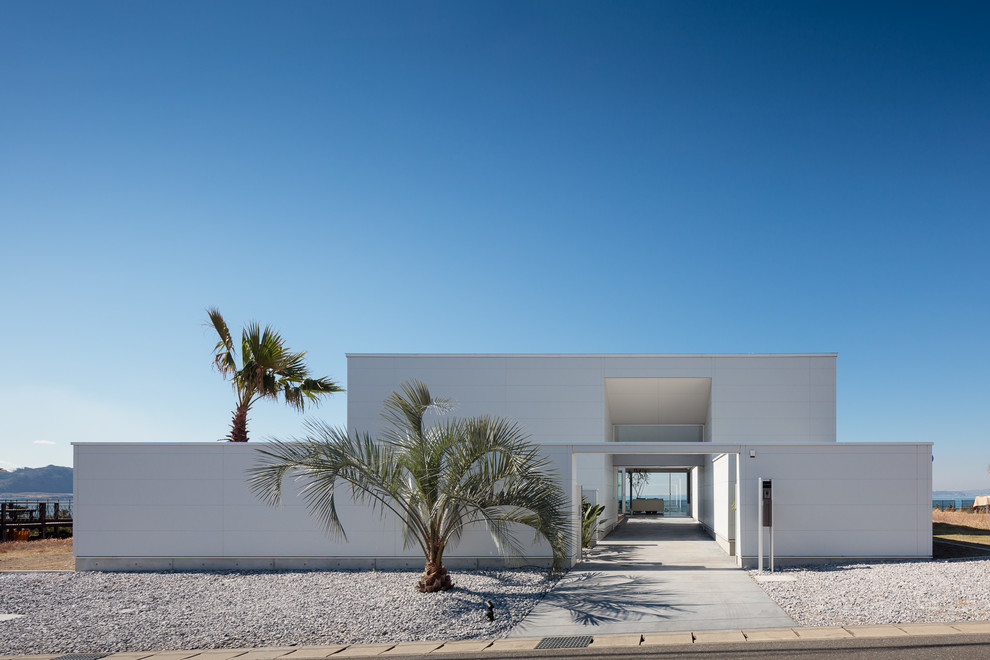 Idées déco pour une façade de maison blanche bord de mer avec un toit plat.