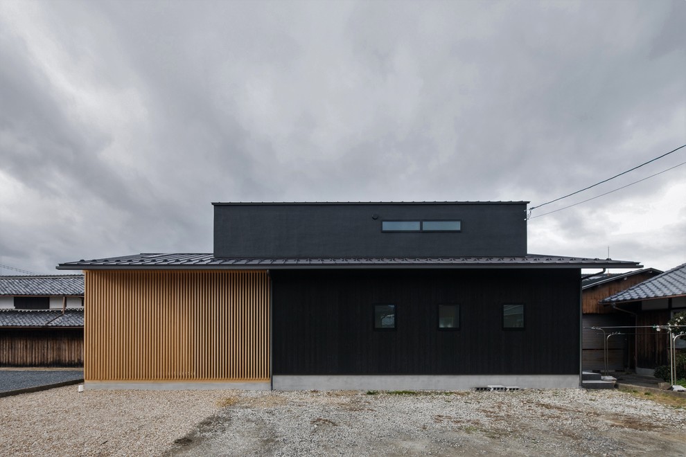 Imagen de fachada de casa negra de estilo zen de tamaño medio de dos plantas con revestimiento de madera, tejado a dos aguas y tejado de metal