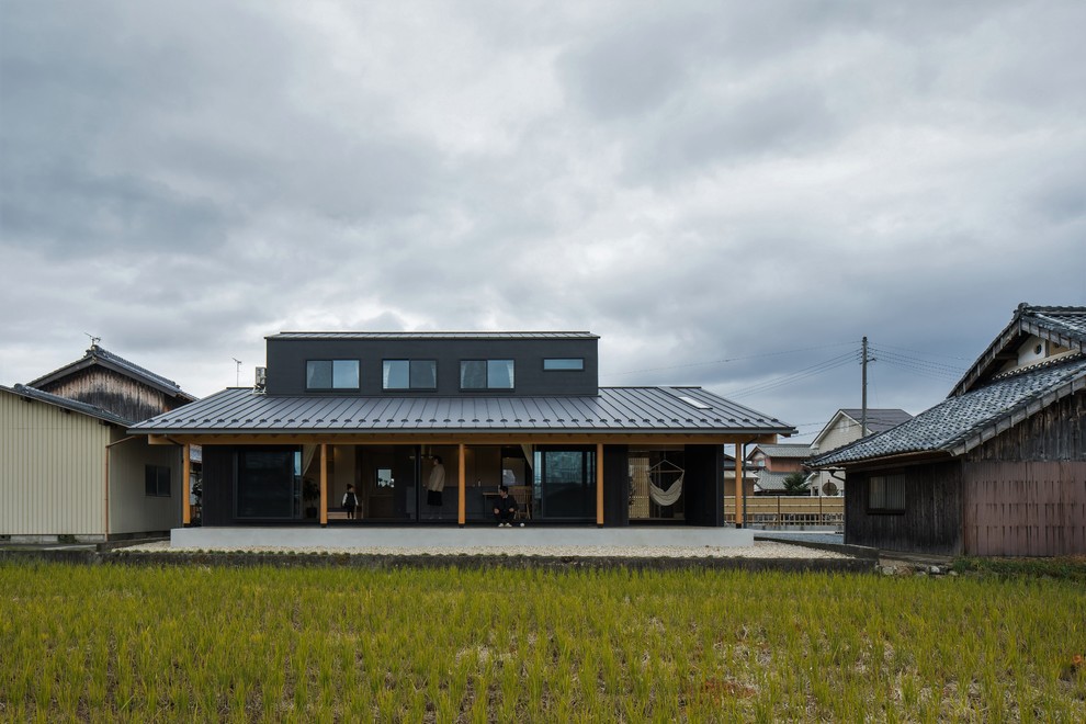 Imagen de fachada de casa negra asiática de tamaño medio de dos plantas con revestimiento de madera, tejado a dos aguas y tejado de metal