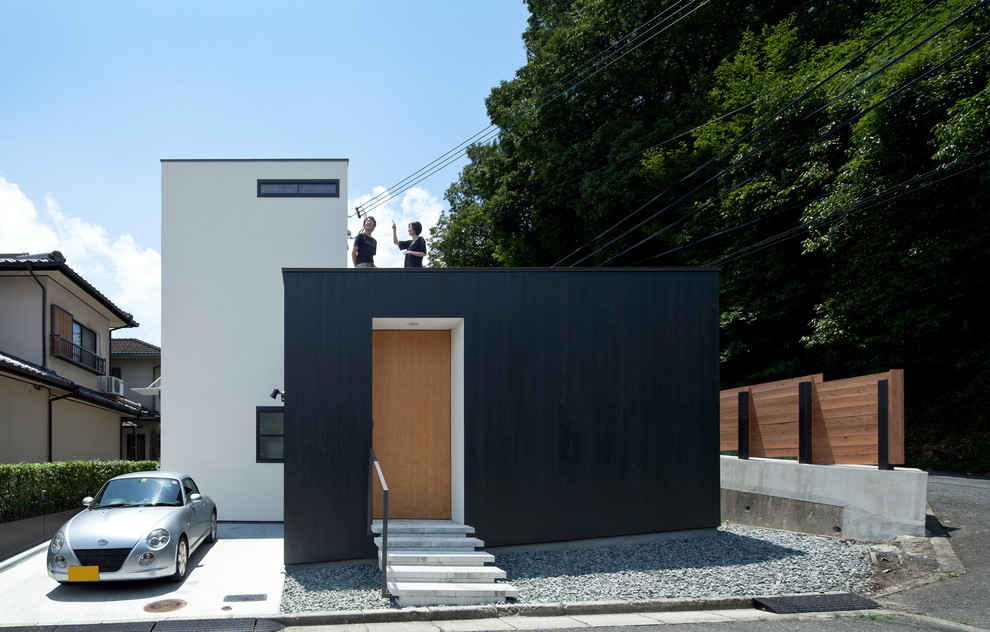 Immagine della villa nera moderna a due piani di medie dimensioni con rivestimento in legno, tetto piano e copertura in metallo o lamiera