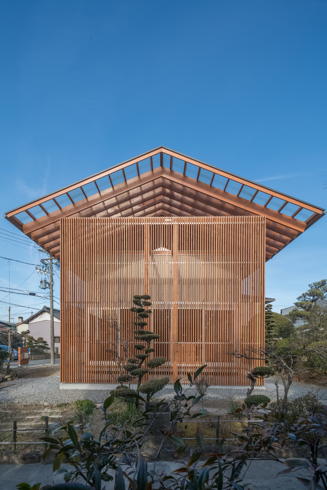 Imagen de fachada marrón moderna de dos plantas con tejado a dos aguas y revestimiento de madera