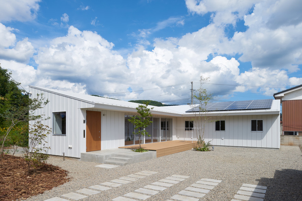 Exempel på ett mellanstort minimalistiskt vitt hus, med allt i ett plan, metallfasad, pulpettak och tak i metall