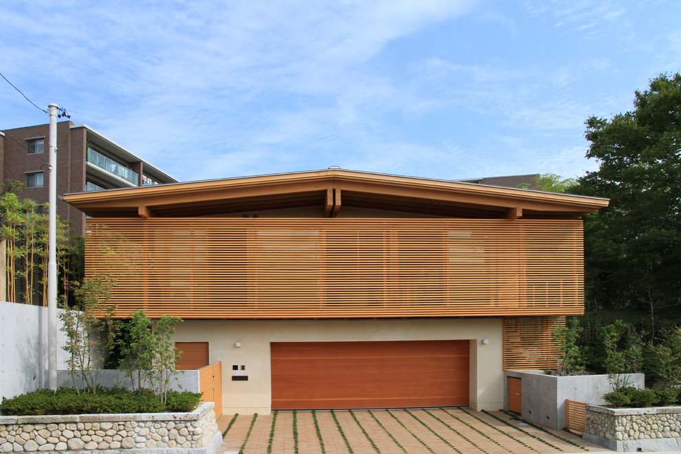 Diseño de fachada marrón de estilo zen de dos plantas con revestimientos combinados y tejado a dos aguas