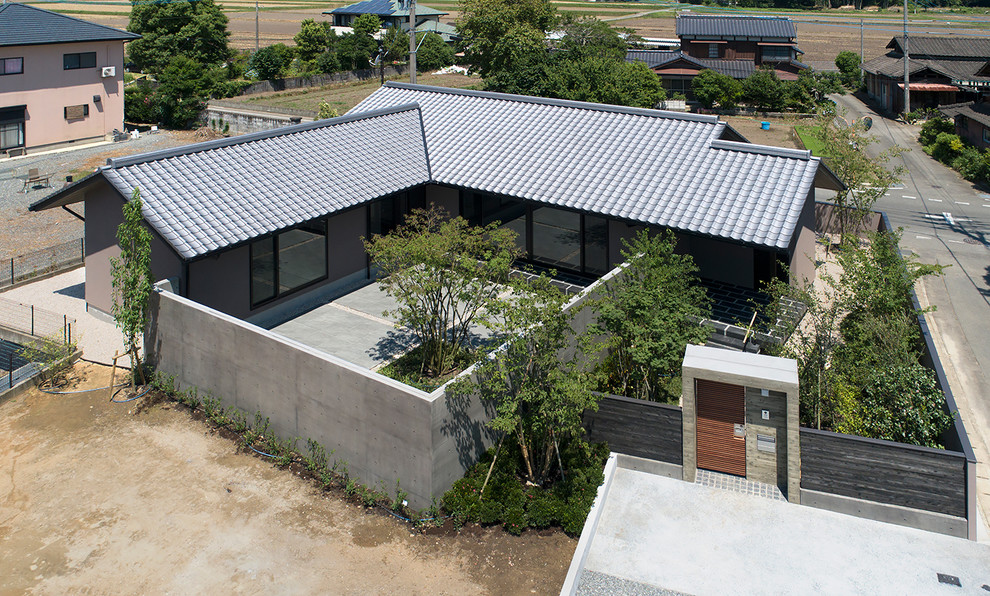 Aménagement d'une petite façade de maison grise asiatique en panneau de béton fibré de plain-pied avec un toit à deux pans et un toit en tuile.