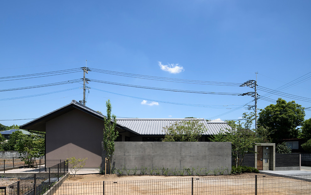 Exemple d'une petite façade de maison grise asiatique en panneau de béton fibré de plain-pied avec un toit à deux pans et un toit en tuile.
