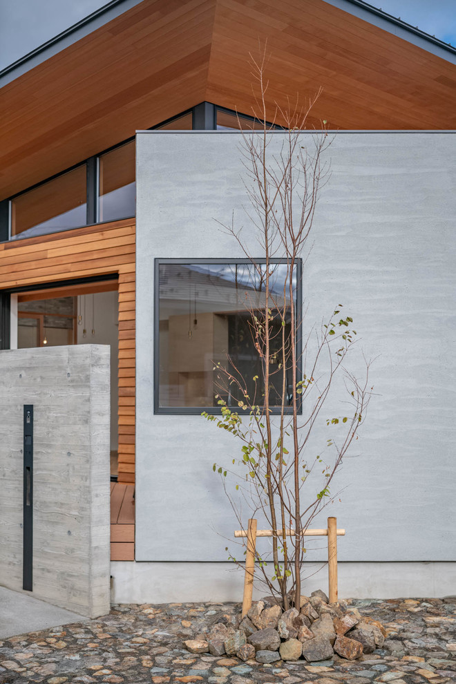 Imagen de fachada de casa gris moderna de tamaño medio de una planta con revestimiento de madera, tejado a cuatro aguas y tejado de metal