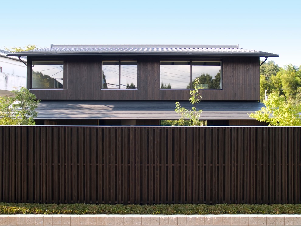Cette photo montre une façade de maison marron asiatique en bois à un étage avec un toit à deux pans et un toit mixte.