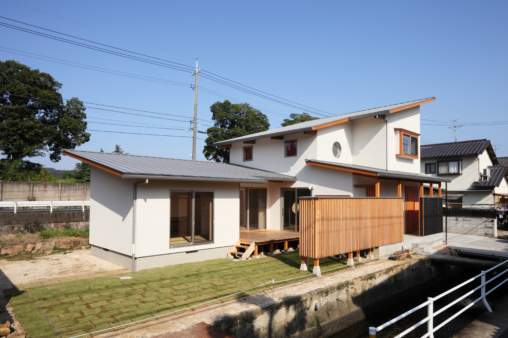 Idée de décoration pour une façade de maison blanche asiatique avec un toit en appentis.