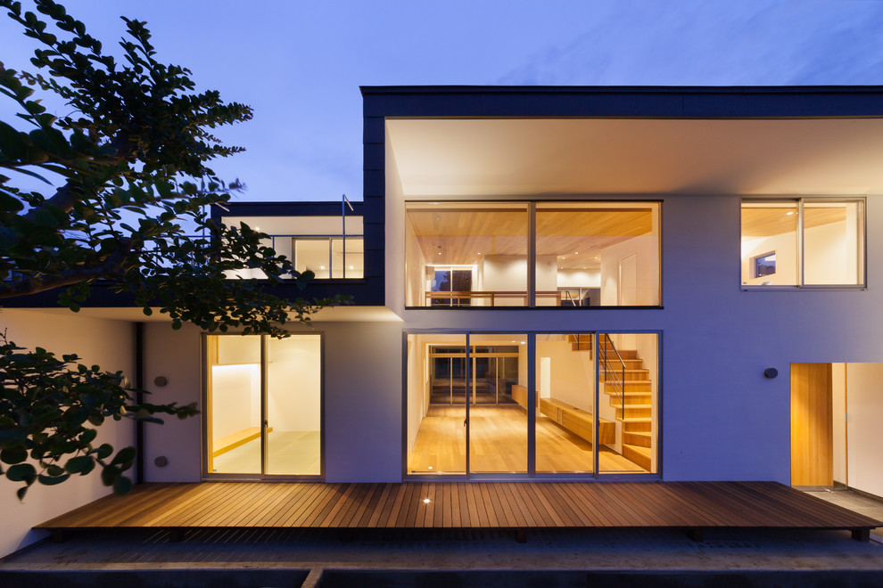 Inspiration pour une grande façade de maison multicolore minimaliste en stuc à un étage avec un toit en appentis et un toit en métal.