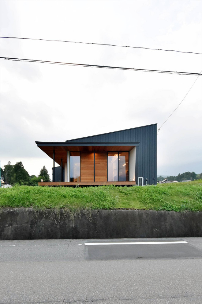 Inspiration pour une façade de maison métallique et noire urbaine de taille moyenne et de plain-pied avec un toit en appentis et un toit en métal.