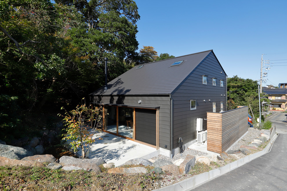 Cette photo montre une façade de maison noire moderne à un étage avec un toit à deux pans et un toit en métal.