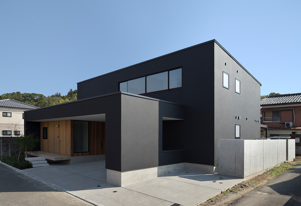 Cette image montre une grande façade de maison noire minimaliste à un étage avec un toit en appentis et un toit en métal.