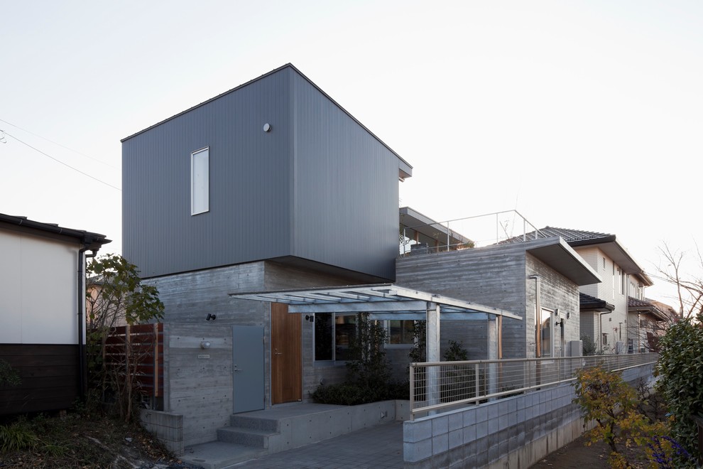 Imagen de fachada de casa gris minimalista grande de dos plantas con revestimiento de hormigón, tejado plano y tejado de varios materiales