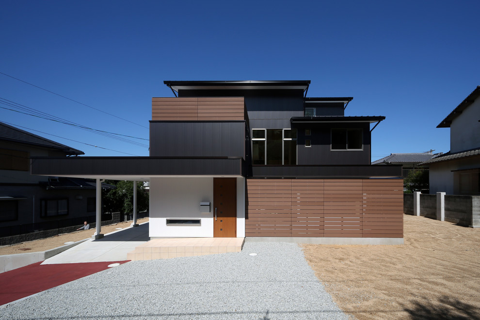 Inspiration pour une façade de maison noire design à deux étages et plus avec un toit plat et un revêtement mixte.