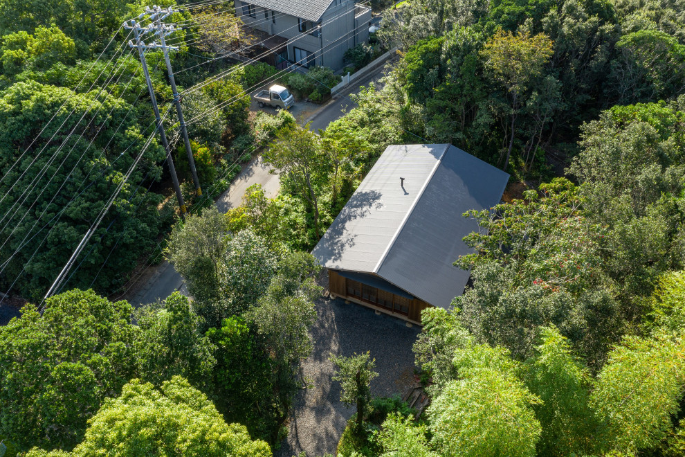 Ejemplo de fachada de casa marrón y gris rústica grande de una planta con revestimiento de madera, tejado a dos aguas, tejado de metal y panel y listón