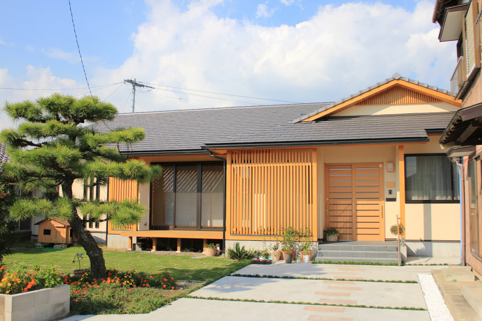 Diseño de fachada de casa beige de estilo zen de tamaño medio de una planta con revestimiento de estuco, tejado a dos aguas y tejado de teja de barro