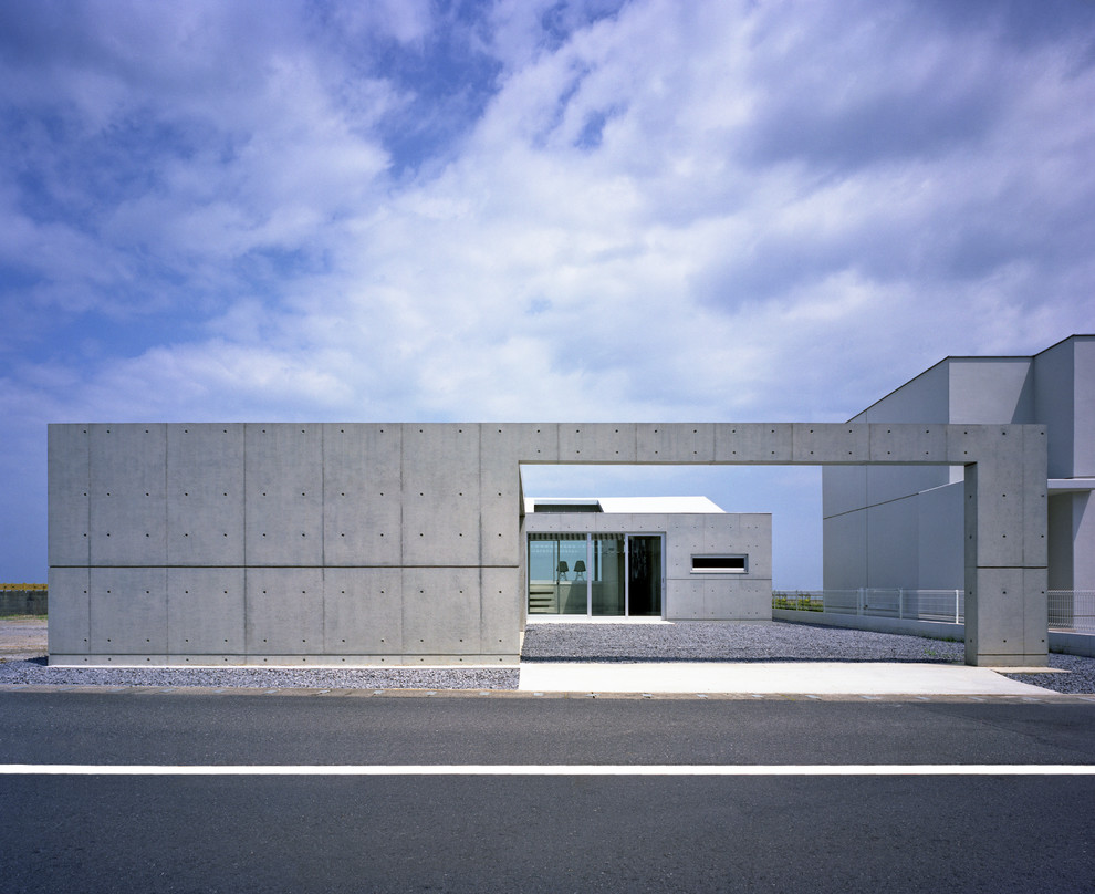 Cette photo montre une façade de maison grise moderne en béton de plain-pied avec un toit plat.