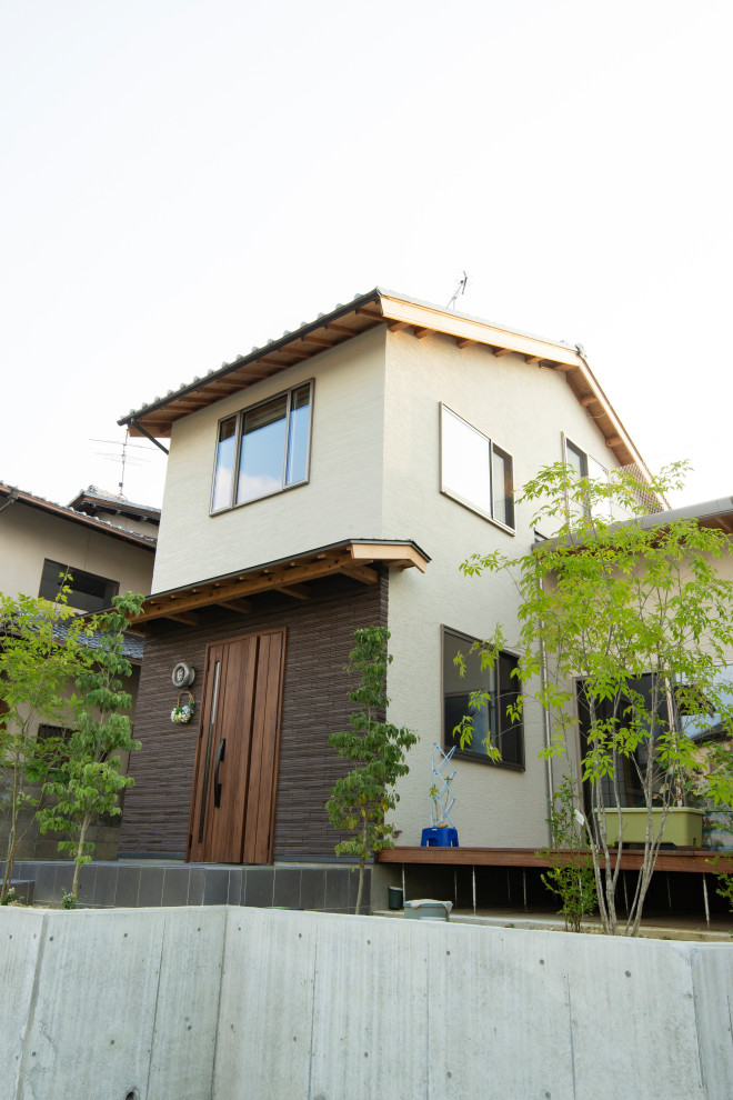 Réalisation d'une façade de maison beige minimaliste de taille moyenne et à un étage avec un toit à deux pans et un toit en tuile.