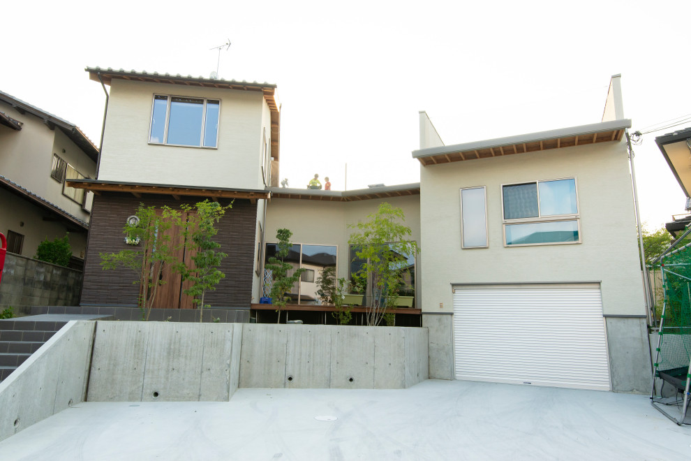 Mittelgroßes Modernes Einfamilienhaus mit beiger Fassadenfarbe, Flachdach und Ziegeldach in Sonstige