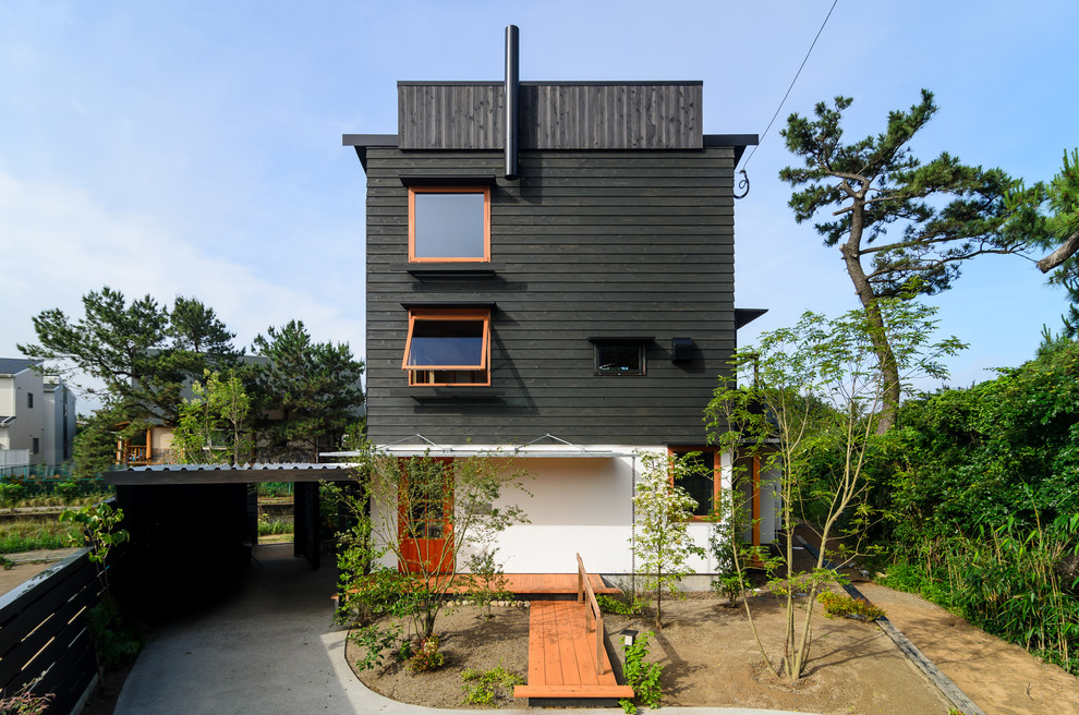 Cette photo montre une façade de maison noire tendance en bois avec un toit plat.