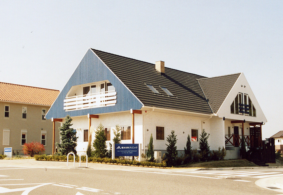 Foto på ett nordiskt vitt hus, med två våningar, tegel, sadeltak och tak med takplattor